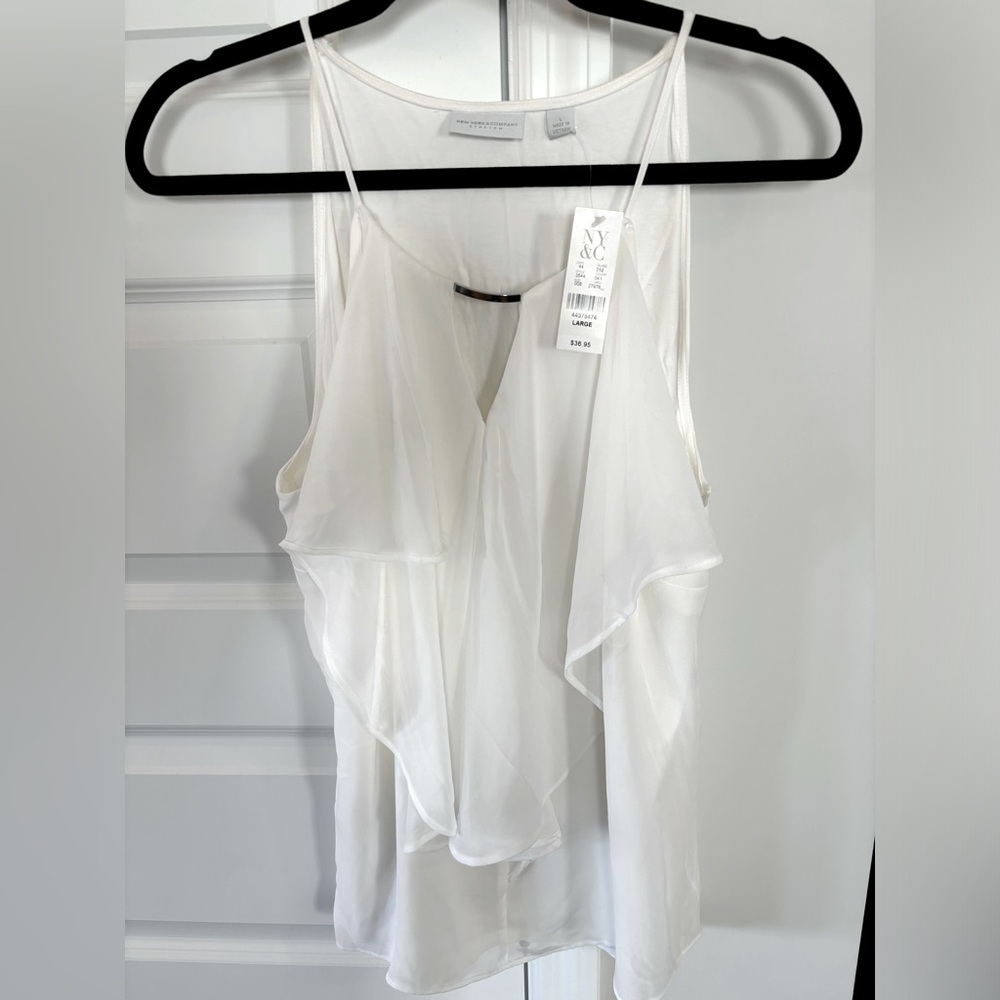 White dressy tank with ruffles and silver bar at chest.